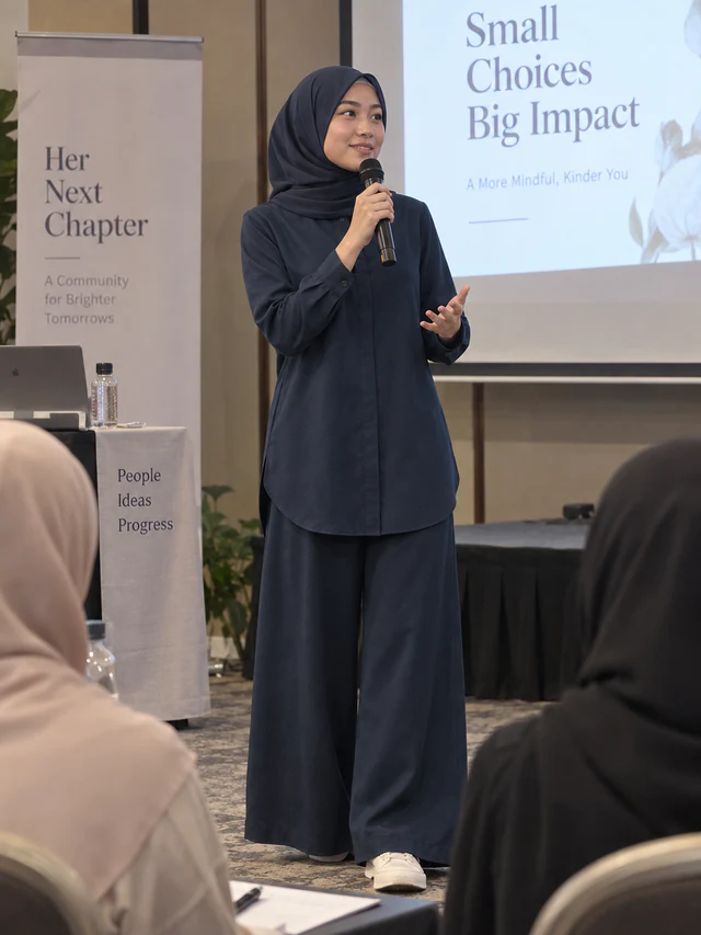 Model memakai Set Elora warna Navy Blue sambil memegang mikrofon dan membuat pembentangan di hadapan peserta seminar.